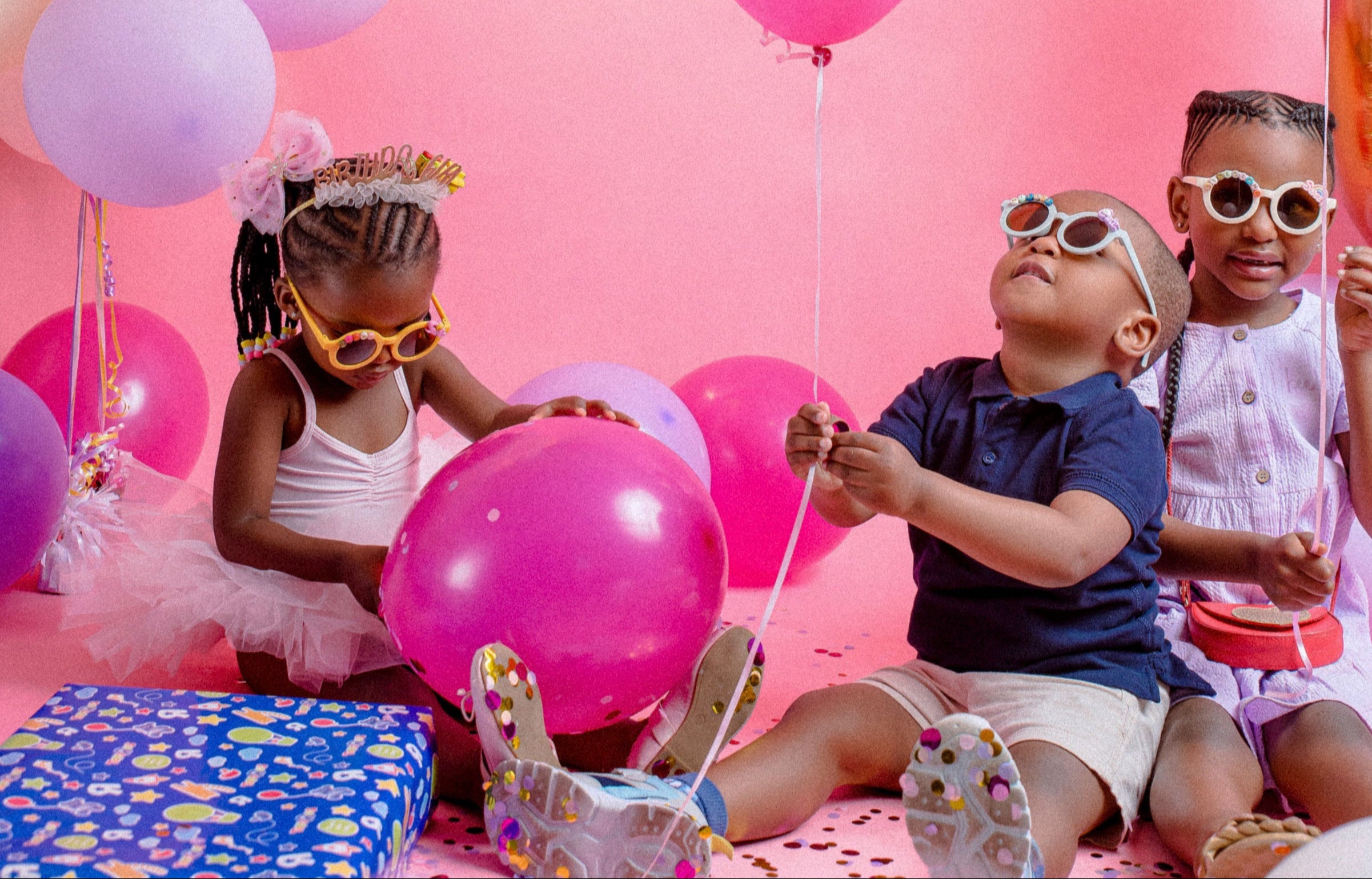 Children playing with balloons on a pink background