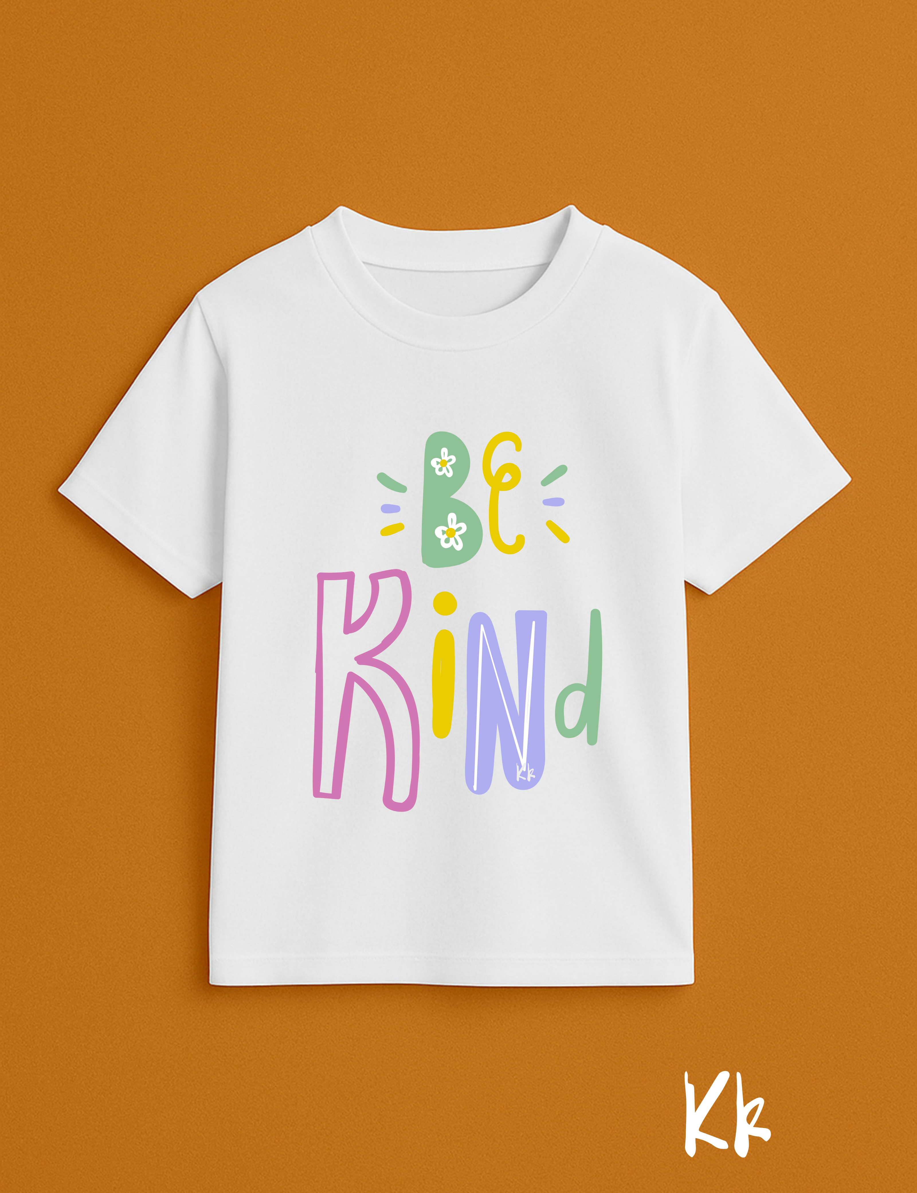 White t-shirt with 'Be Kind' text in colorful letters on a brown background