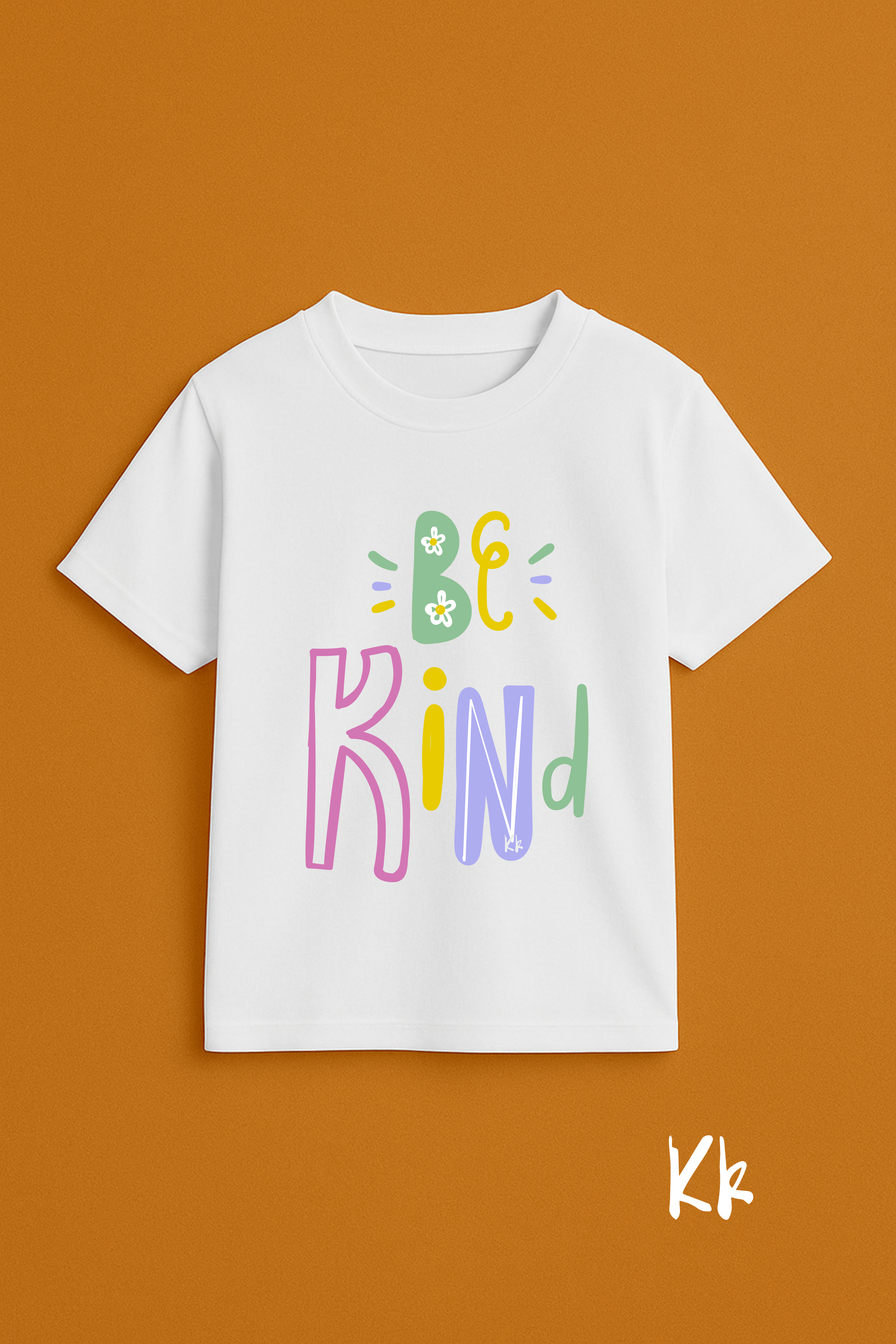 White t-shirt with 'Be Kind' text in colorful letters on a brown background